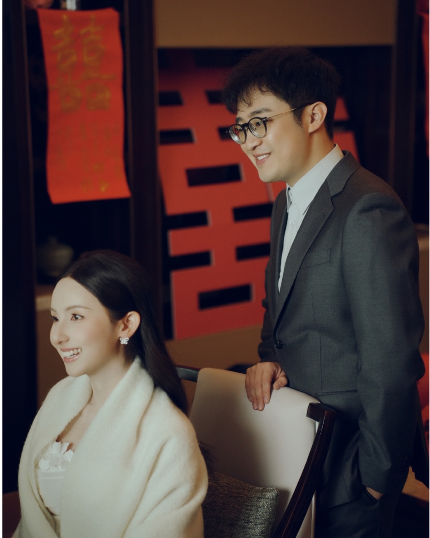 杭州西湖婚礼，新人坐在红色喜字前自然地笑