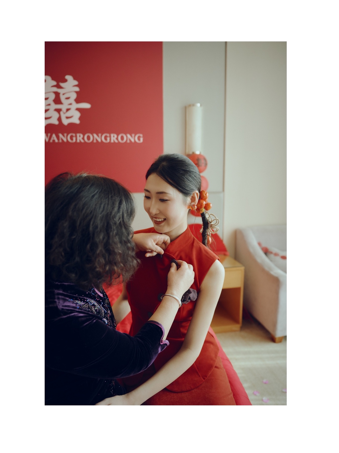 母亲低头为新娘整理红色礼服