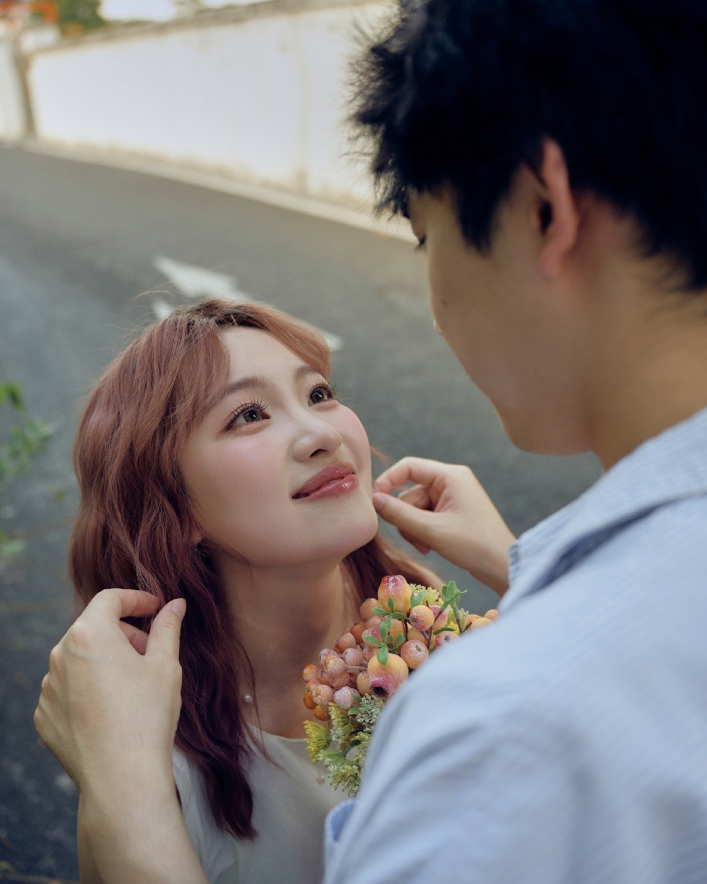 男生替女生整理头发,女生捧着花束抬头看向他